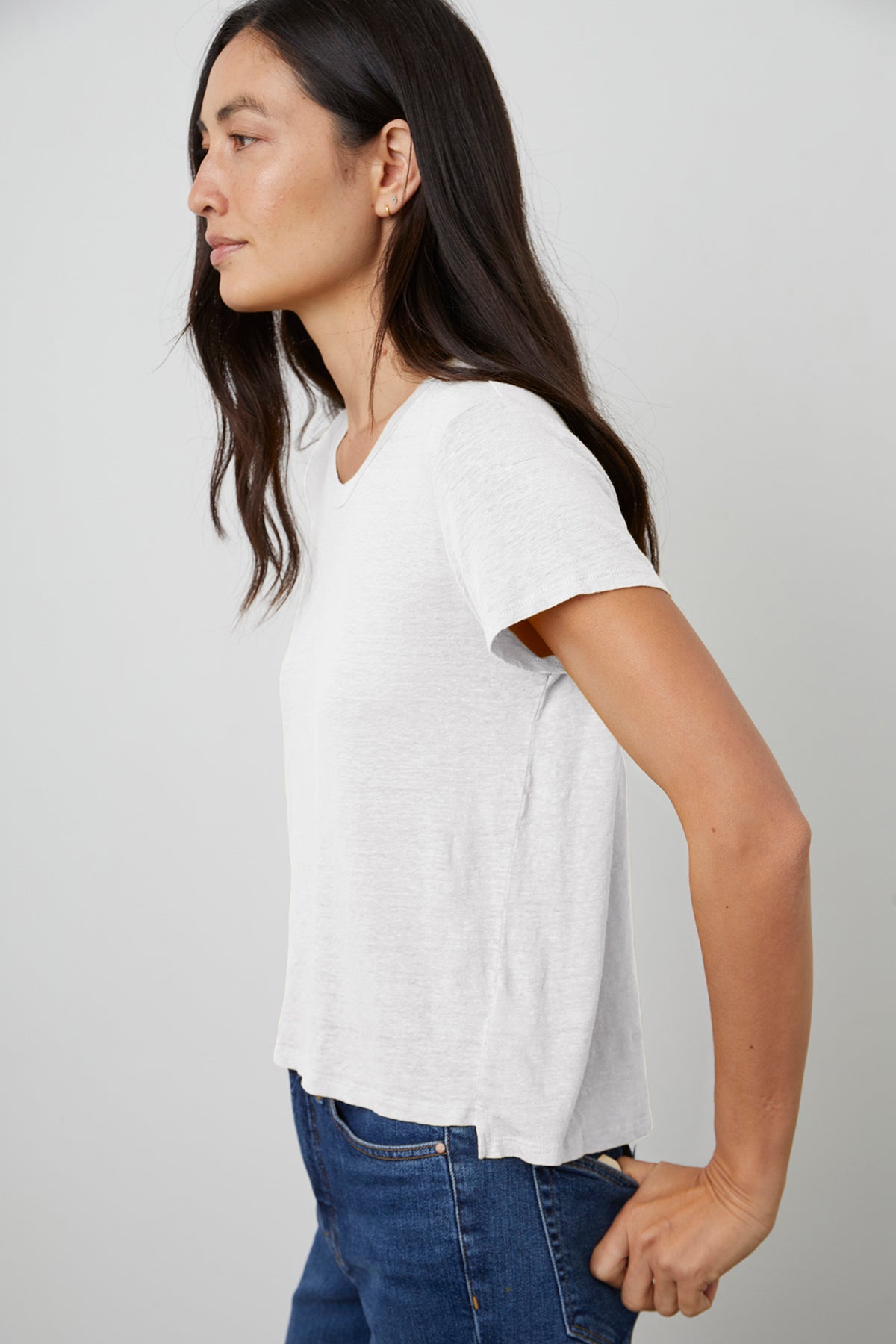 Casey Crew Neck Tee in White with Model Standing to the Side to Show Hem Detail.