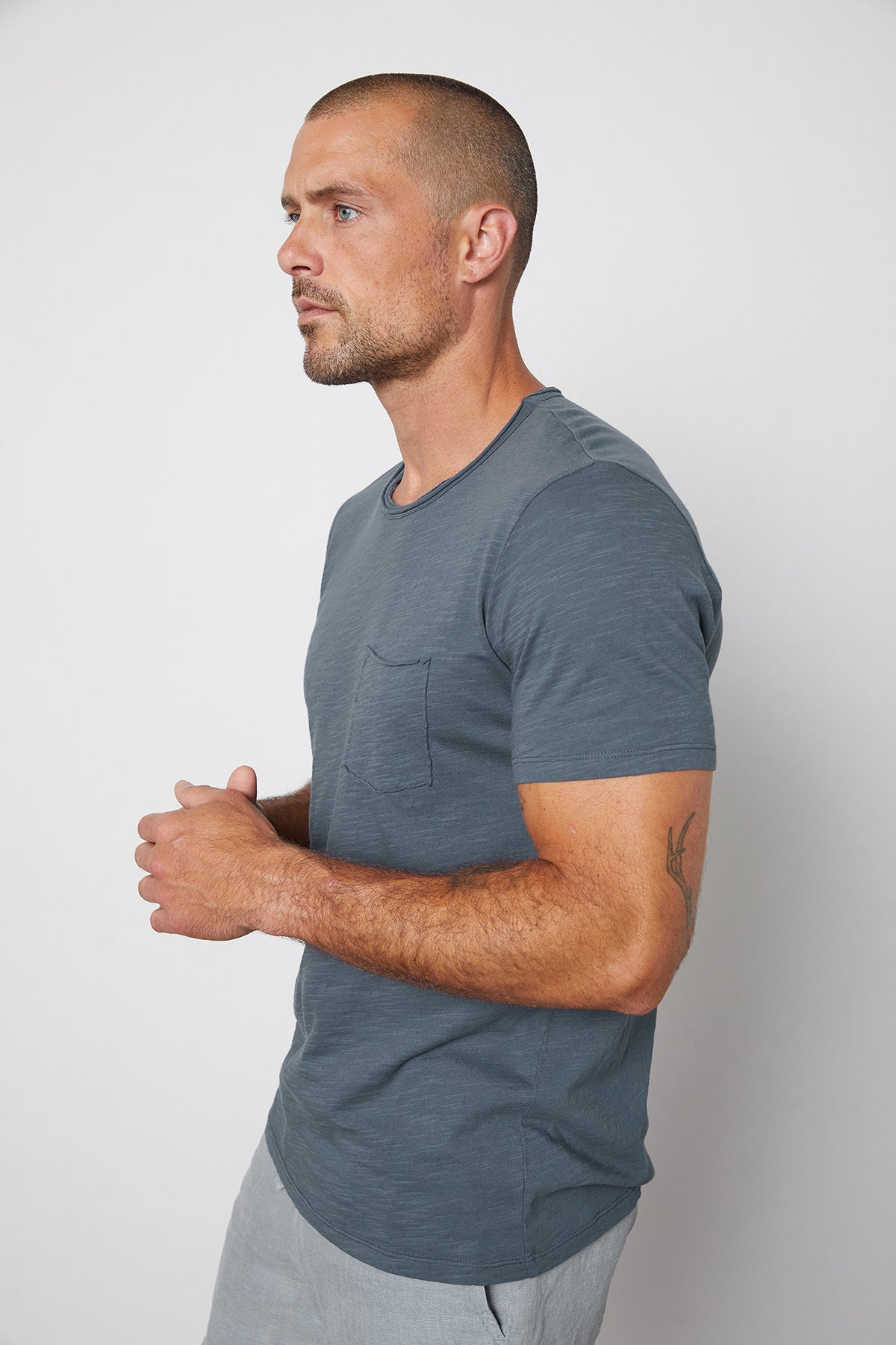   Side view of Chad slub cotton short sleeve tee with raw edges and front pocket in malachite. 